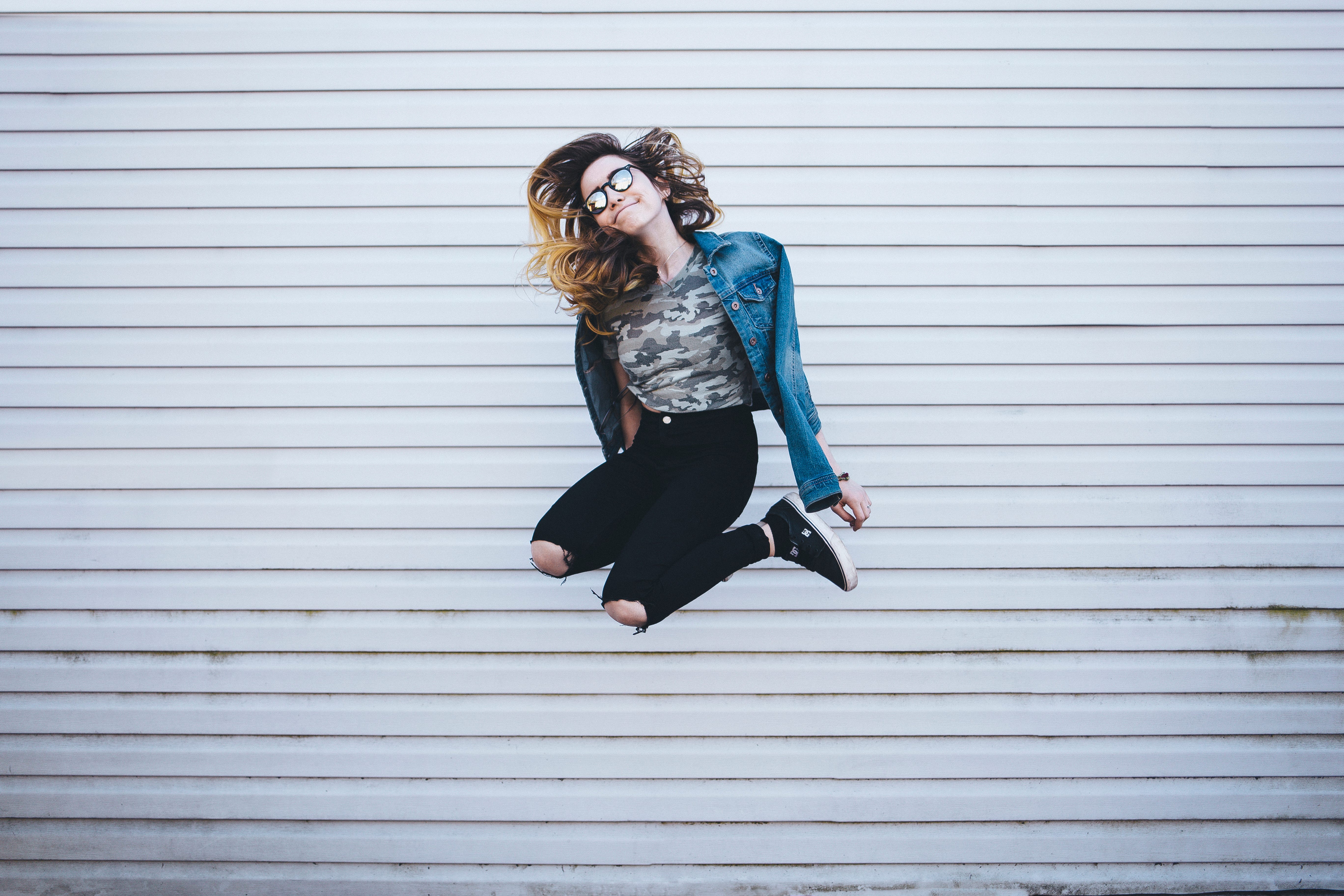 A woman jumping in front of a light-coloured wall – energy and new possibilities